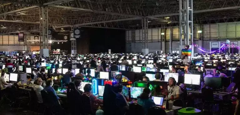 A room full of computers set up with teams of people competing on halo at insomnia