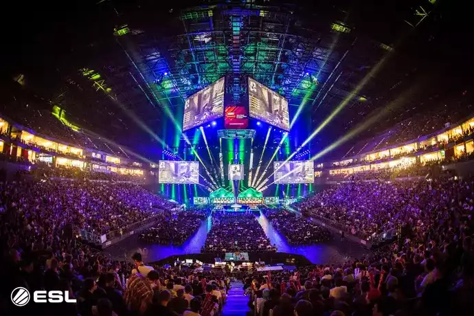 A crowd seated at the arena next to a light up stage for the latest ESL tournament