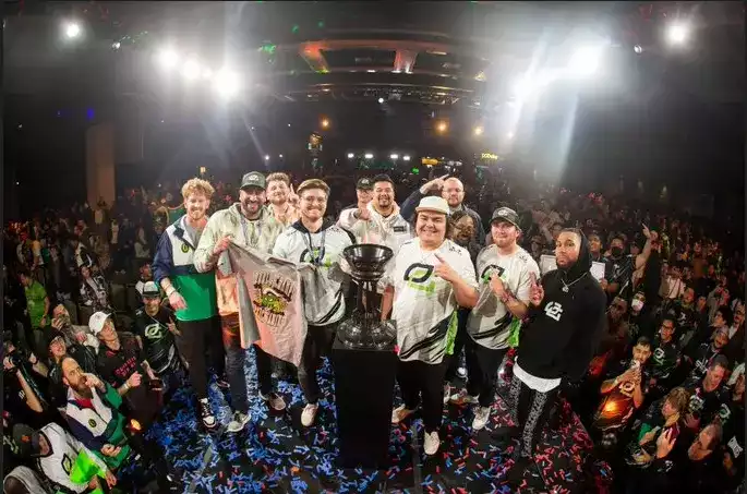 OpTic on stage posing next to the trophy after their championship win while the crowd watches